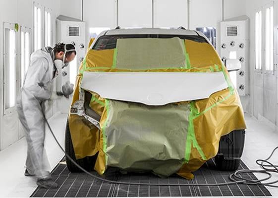 Auto body technician painting a vehicle.